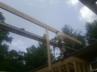 Carpenter setting a ridge beam over a new addition frame — Ice Dam Removal by Roofing Brothers in Sneads Ferry