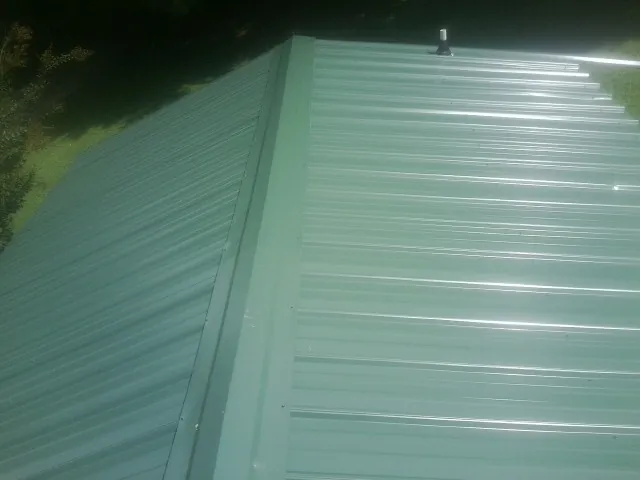New green metal panels meeting at the ridge of a roof — Flat Roof Repair work by our crew in Sneads Ferry