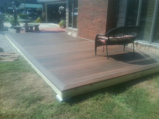 New wood deck and wicker chair beside a brick house in Sneads Ferry