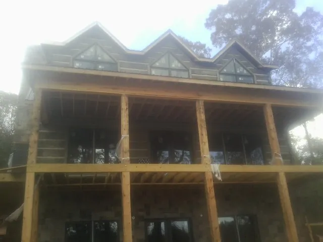 Dormers and porch framing on a large log home under construction — Roof Coating work by our crew in Sneads Ferry