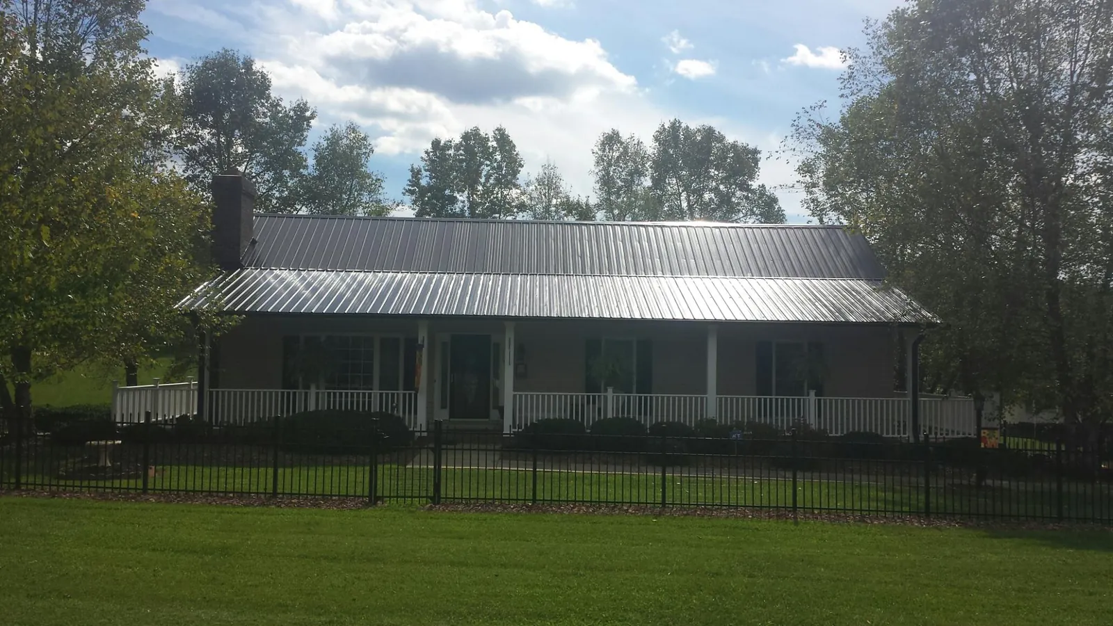 Gray metal roof on a brick ranch with a full width front porch — Gutter Guard Installation work by our crew in Sneads Ferry