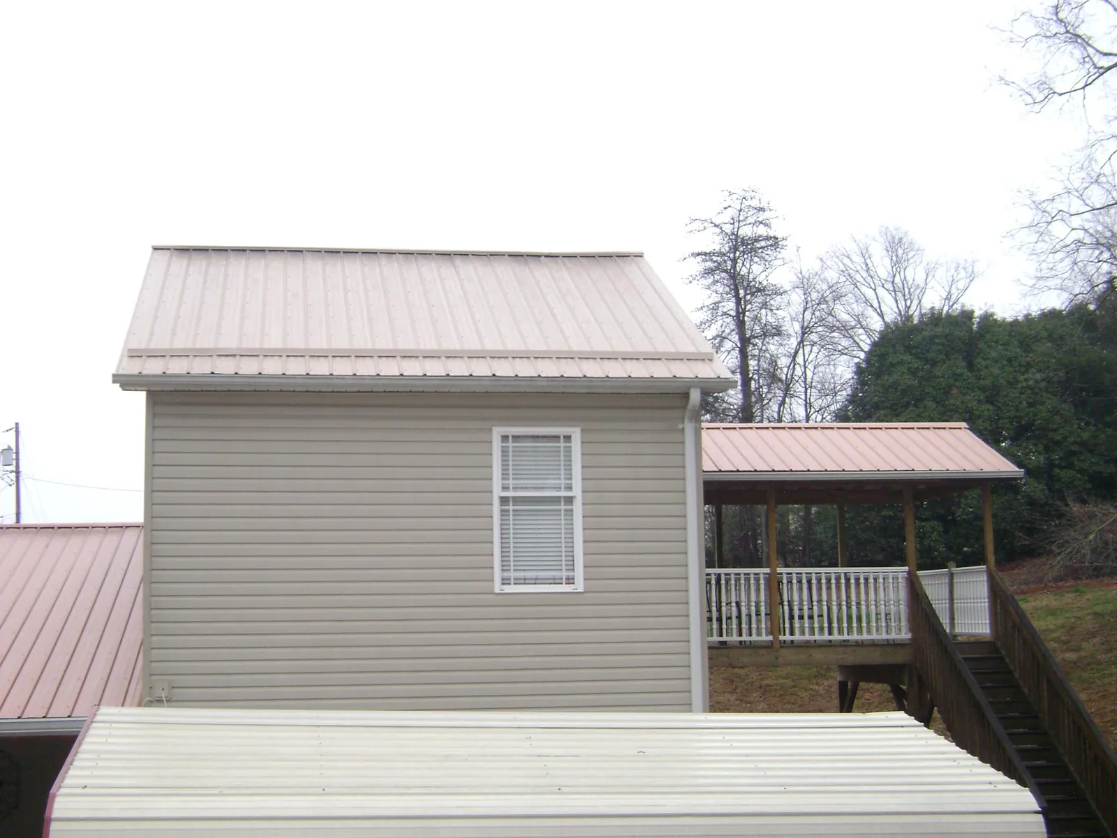 Tan metal roofs on a two story addition and attached porch, from a Roof Replacement job in Sneads Ferry