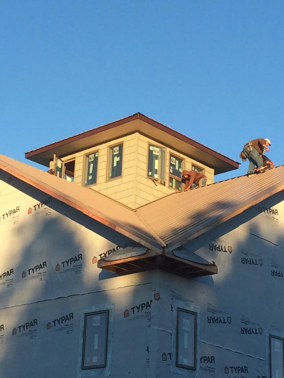 Roofers working around a rooftop cupola on a new metal roof at sunset — Roof Waterproofing in Sneads Ferry by Roofing Brothers